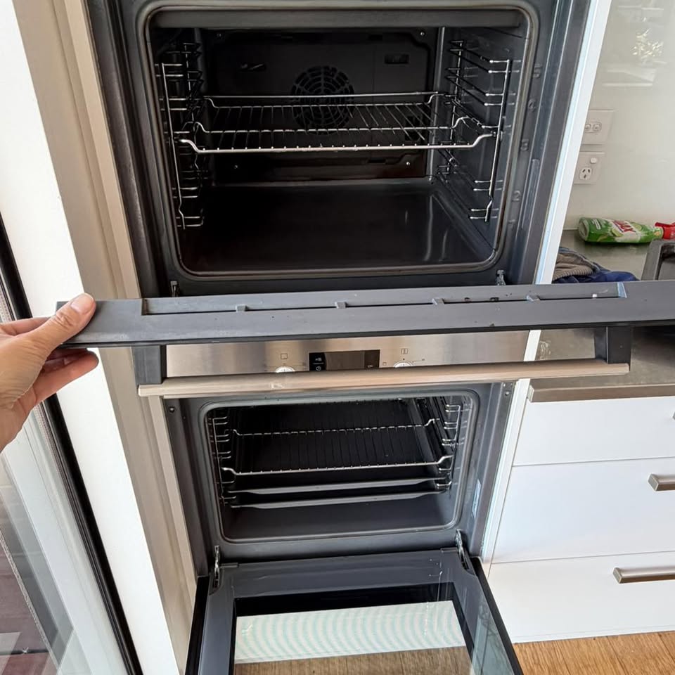 A double oven door removed and set out during a deep clean